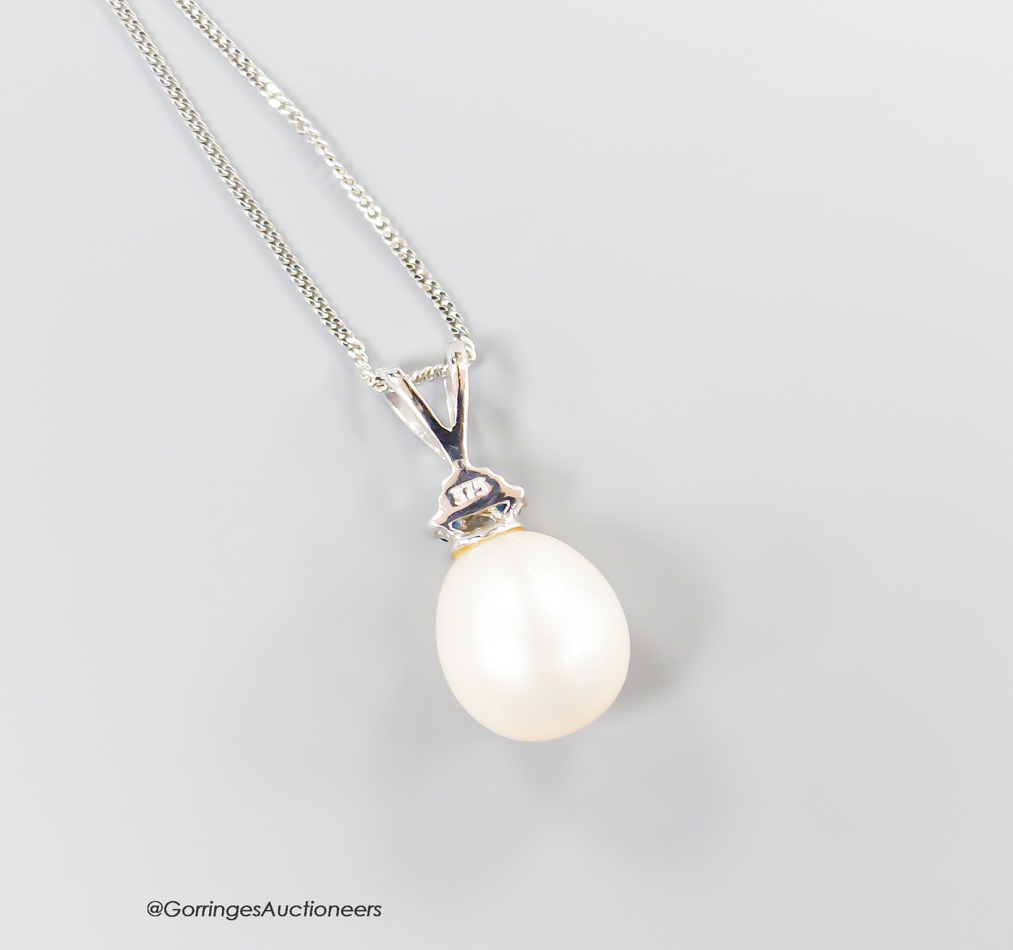 A modern Moire 375 white metal, single stone cultured pearl and three stone sapphire set pendant, 20mm, on a 375 chain, 43cm.